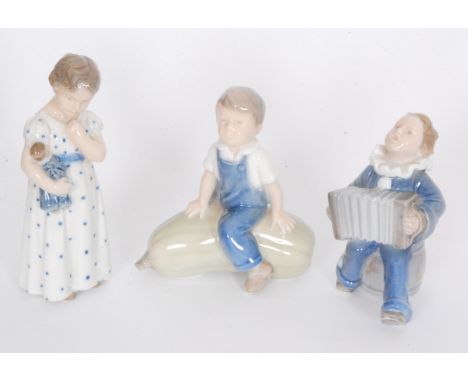 Three small Royal Copenhagen figures comprising a boy playing an accordion, model 3667, a boy sat on a marrow, model 4539 and