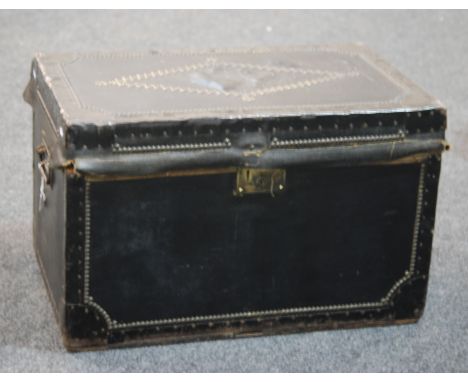 An early 20th Century black leather trunk with twin iron handles and rivet details to borders, opening to single web tray and