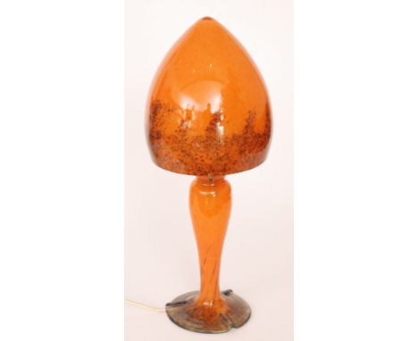 A contemporary studio glass table lamp, in the style of Monart with a mottled orange pedestal and cone shaped shade with brow