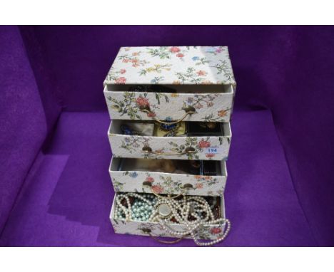 A four drawer retro cardboard chest containing a selection of costume jewellery and strings of beads including simulated pear