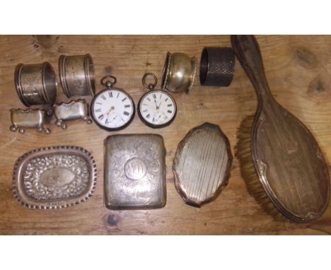 A box of assorted hallmarked silver comprising four napkin rings, two pocket watches, a compact, a pin dish, a cigarette case