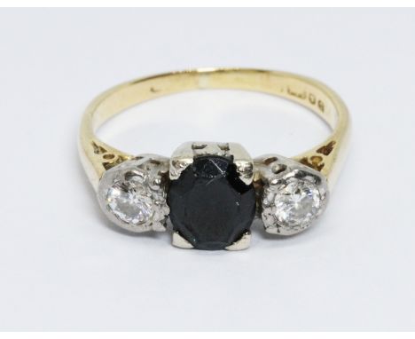 A diamond and sapphire ring, the central dark blue oval cut stone measuring approx. 7.10mm x 5.85mm, the two diamonds weighin