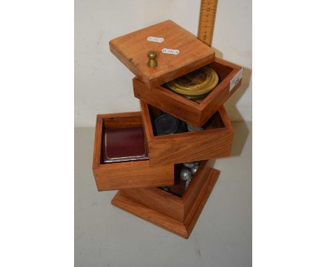 An unusual rotating square storage box with assorted contents to include a compass, coins, white metal place card holders etc