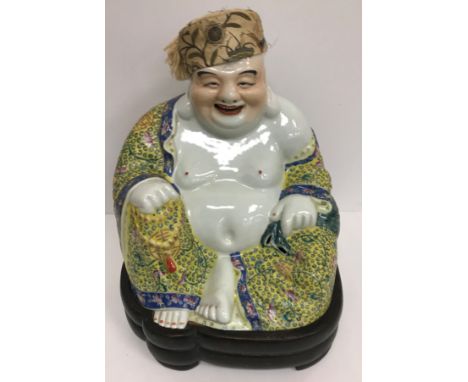 A Chinese porcelain figure of a seating smiling Buddha in a yellow ground famille rose gown bearing impressed seal mark to ba