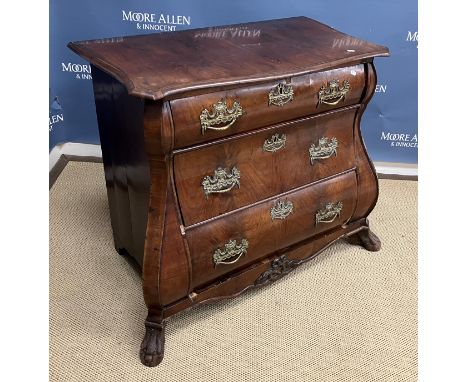 An 18th Century Dutch walnut commode of bombé form, the top with moulded edge over three graduated drawers, each with ornate 