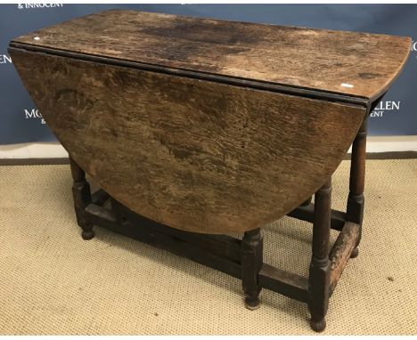 A 19th Century oak oval gate-leg drop-leaf dining table on turned supports united by stretchers, 140 cm wide x 108.5 cm deep 