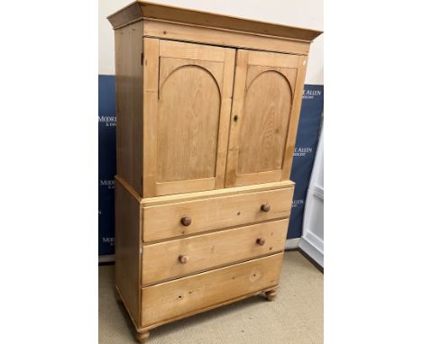 A Victorian waxed pine linen press, the canted cornice over two arched panelled cupboard doors enclosing a single shelf over 