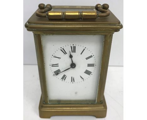 A circa 1900 brass cased carriage clock of typical form, the enamelled dial with Roman numerals to the chapter ring raised on