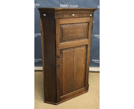 An oak hanging corner cupboard with twin fielded panelled door enclosing three shelves, 87 cm wide x 127 cm high, a modern pi