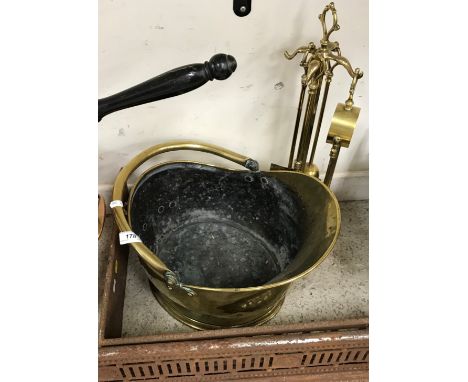 A late Victorian brass helmet shaped coal scuttle and an early 20th Century brass fireside companion set together with a cast