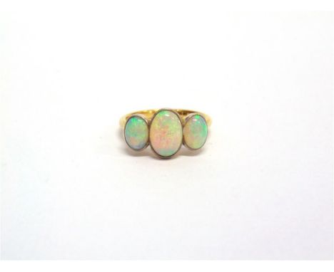 A THREE STONE OPAL RING stamped '18ct' and 'Plat', the graduated oval cabochons millegrain set, finger size L1/2, 3.2g gross