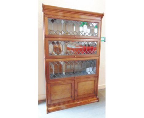 AN OAK GLOBE WERNICKE TYPE BOOKCASE,  three lead glazed sections over cupboard base section, 87cm wide 36cm deep 146cm high