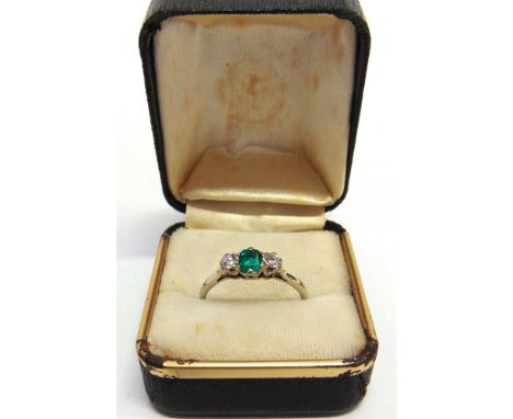 A DIAMOND AND EMERALD THREE STONE RING the step cut stone flanked by brilliant cuts totalling approximately 0.15 carats, the 