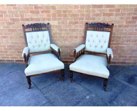 A PAIR OF EDWARDIAN BUTTON UPHOLSTERED ARMCHAIRS  with carved wooden frames