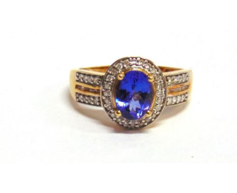 A TANZANITE AND DIAMOND 18 CARAT GOLD RING the oval cut stone twenty four small brilliant cuts with two lines of small brilli