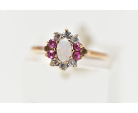A 9CT YELLOW GOLD CLUSTER RING, centering on an oval opal cabochon, in a surround of six colourless cubic zirconia and four r