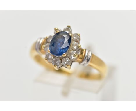 AN 18CT GOLD SAPPIRE AND DIAMOND CLUSTER RING, centering on a raised oval cut blue sapphire, within a surround of ten round b