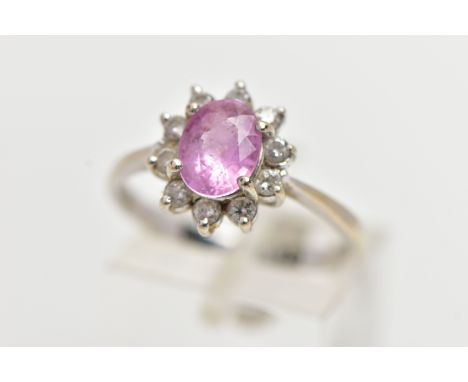 AN 18CT WHITE GOLD PINK SAPPHIRE AND DIAMOND CLUSTER RING, centering on a four claw set, oval cut pink sapphires, within a su