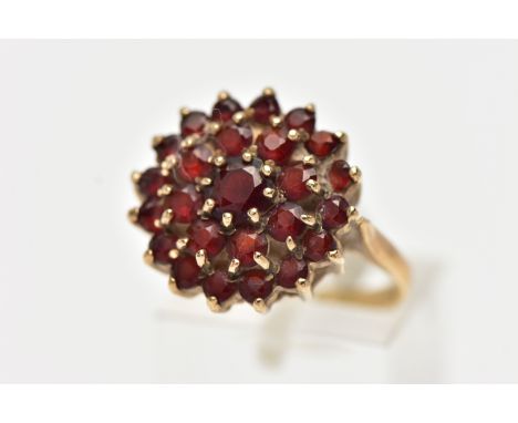 A 9CT YELLOW GOLD GARNET CLUSTER RING, large cluster of circular cut garnets, approximate cluster width 17.4mm, to a polished