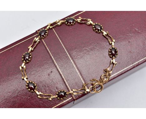 A 9CT YELLOW GOLD GARNET BRACELET, set with seven garnet cabochons, each claw set to a collet mount, interspaced with two bar