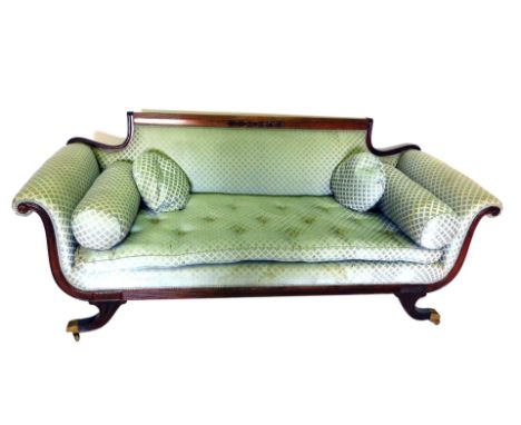 A Regency style mahogany sofa, in green upholstery, with straight reeded upper rail, scroll arms, raised on cornucopia legs, 