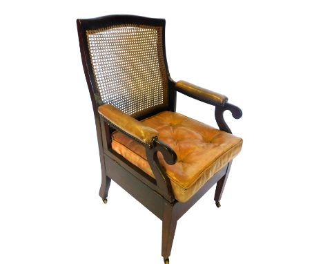 A 19thC Carter's mahogany commode armchair, with a caned back, hinged sides with brown leather pads, a brown leather buttoned
