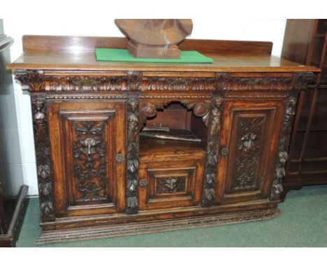 A Victorian carved oak sideboard with low raised back, three frieze drawers, central open shelf above small cupboard flanked 