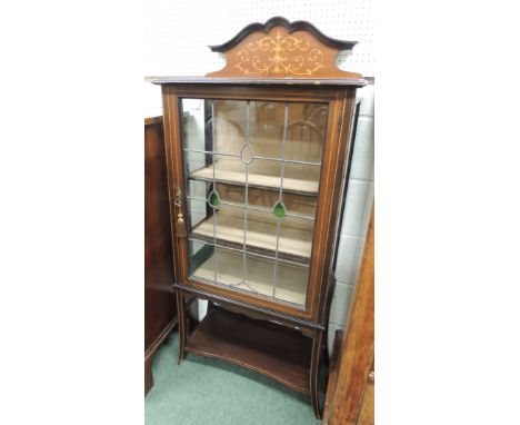 An early 20th century display cabinet, having inlaid raised back, leaded glass door enclosing two shelves and shaped supports