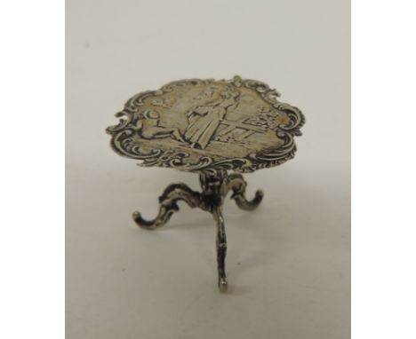 A 19th Century Continental miniature circular pedestal table with embossed decoration of lady holding a basket within shaped 