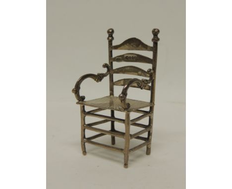 An 18th Century Dutch scarce miniature silver model of a four-slat ladder back chair with decorative scrolling arms, solid se