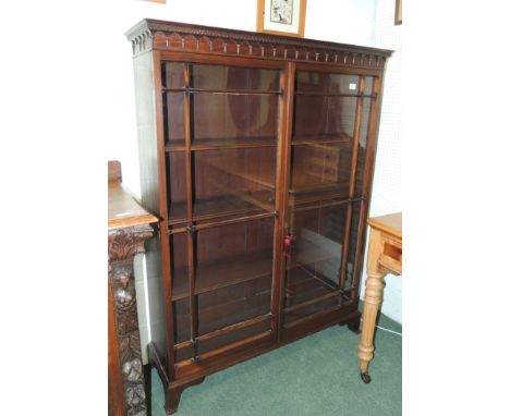 An early 20th century mahogany bookcase with dentil cornice, astragal glazed doors, enclosing three adjustable shelves and on