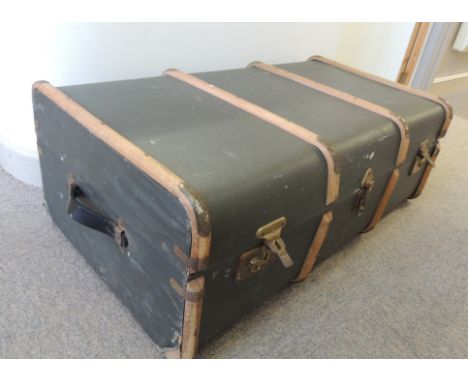 A wood banded travelling trunk containing a large quantity of 20th Century table linen, cushion covers, clothing etc