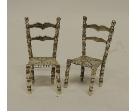 A pair of Continental miniature silver ladder back chairs with turned supports and "rush" seats, 5cms high (2)