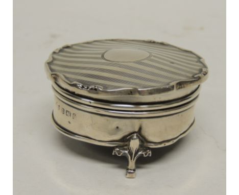 A circular silver trinket box, the hinged cover with lined detail and with shaped edge, velvet lined interior and on three sh