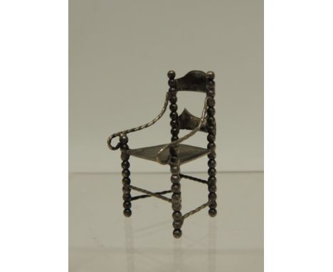 A small 19th Century miniature silver chair, German Hannau marks, having slightly curved ladder back, bobbin supports, thin t