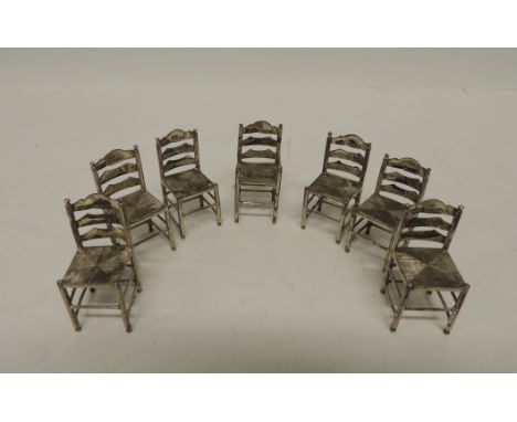 A set of seven (6 standard and one carver) Dutch miniature ladder back chairs with "rush" seats and rounded supports and stre