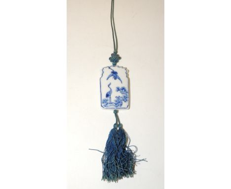 A 20th Century Japanese blue and white glazed ceramic pendant painted with cranes  and a pine branch, on knotted silk thread 