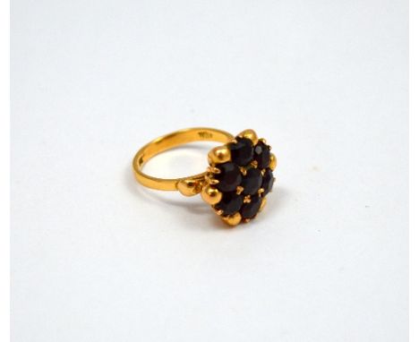 AN 18CT GOLD GARNET DRESS RING, with six circular faceted garnets within a flower cluster shape, stamped 18ct, ring size //