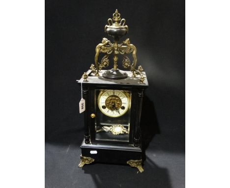     An Ebonized Mantel Clock With Circular Dial &amp; Visible Movement, The Case Mounted With Cherubs                        