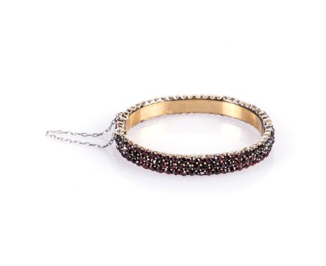 A BOHEMIAN GARNET BANGLE, LATE 19TH CENTURY hinged bangle set with rose cut garnets in pinchbeck in a rose gold colour 