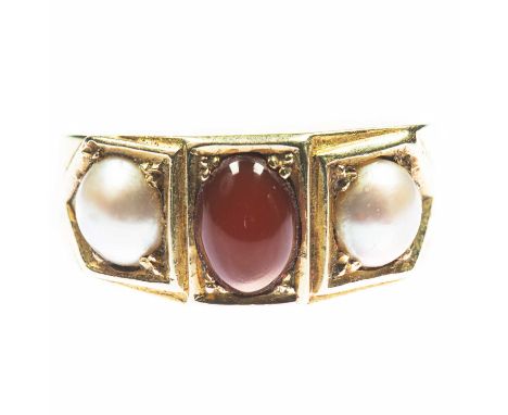 A CARNELIAN AND SPLIT PEARL THREE STONE RING an oval carnelian spaced by split pearls to a tapering band. Unmarked, ring size