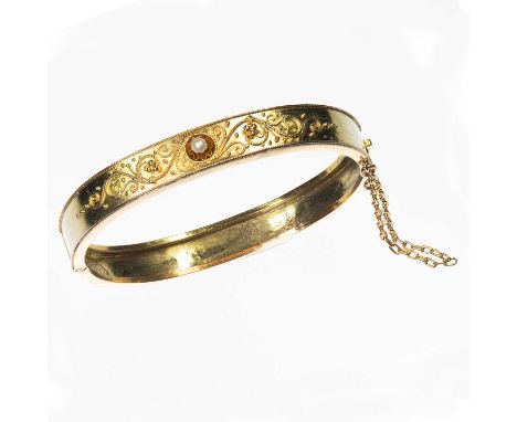 A LATE 19TH CENTURY SEED PEARL HINGE OPENING BANGLE the front set with a seed pearl within a fancy cannetille scroll design, 
