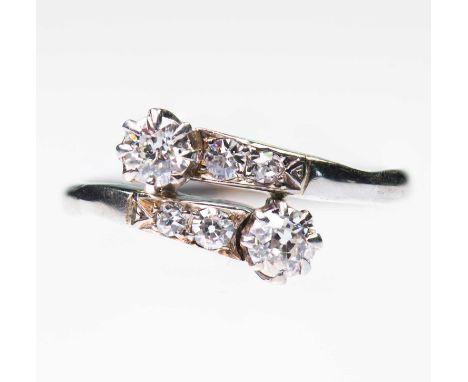 AN EARLY 20TH CENTURY DIAMOND CROSSOVER RING two old-cut diamonds in claw settings to diamond-set bypass shoulders. Estimated