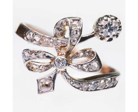 A DIAMOND CROSSOVER RING an old-cut diamond tied by a diamond-set ribbon bow. Estimated total diamond weight 0.15ct, marked '