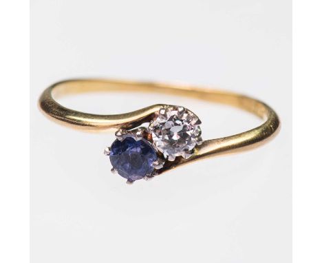 AN EARLY 20TH CENTURY SAPPHIRE AND DIAMOND TWO STONE RING a round-cut sapphire and an old-cut diamond to bypass scroll should