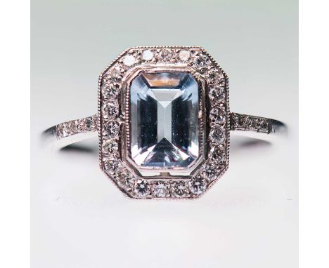 AN AQUAMARINE AND DIAMOND CLUSTER RING an octagonal-cut aquamarine within a conforming milgrain border of round brilliant-cut