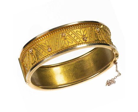 A 19TH CENTURY ETRUSCAN REVIVAL HINGE OPENING BANGLE the front with applied foliate cannetille decoration. Unmarked, 4cm by 5