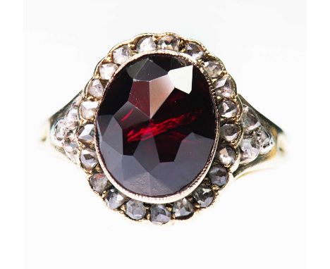 A GARNET AND DIAMOND CLUSTER RING an oval rose-cut garnet within a border of rose-cut diamonds, to a tapering band. Unmarked,