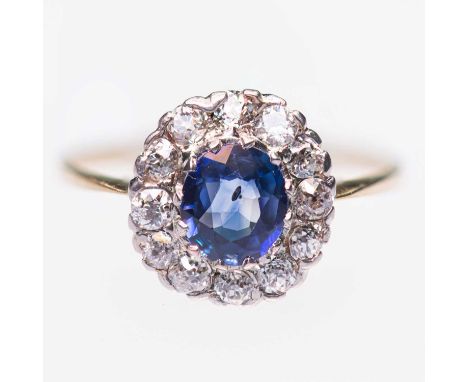 AN EARLY 20TH CENTURY SAPPHIRE AND DIAMOND CLUSTER RING an oval-cut sapphire within a border of old-cut diamonds. Estimated t