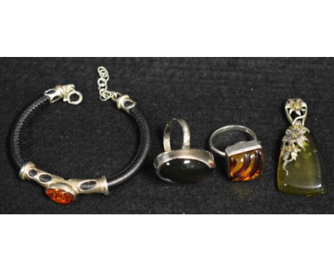 A silver mounted amber and black leather bracelet, oval amber panel arched tubular surround, sprung clasp, stamped 925;  a pe